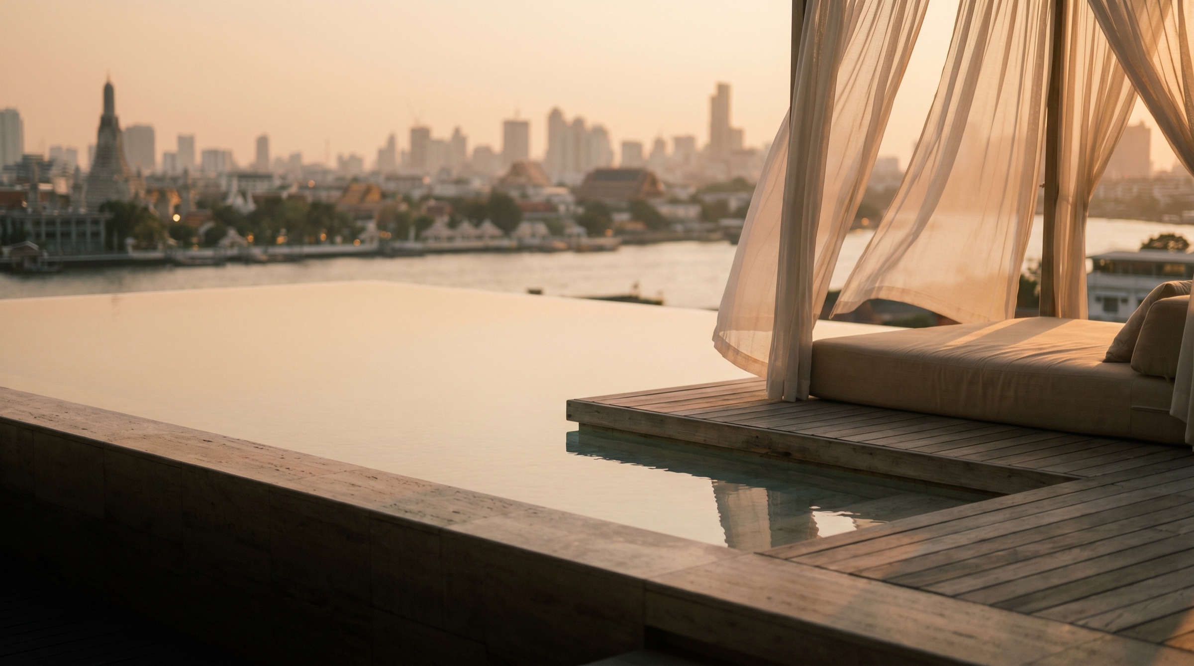 A Bangkok rooftop at golden hour, the river and Wat Arun beyond